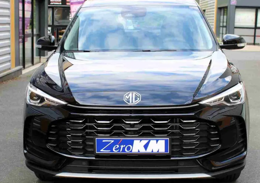 Vue intérieure côté conducteur du MG ZS 1.5L HYBRID+ 2026 en Pebble Black Metal, sièges tissu gris et noir, volant cuir multifonction.