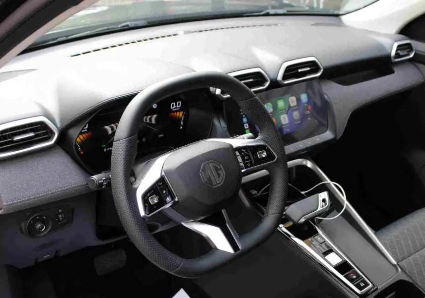 Vue frontale de l'intérieur du MG ZS 1.5L Hybrid+ 2026, avec volant multifonction et écran tactile central allumé.