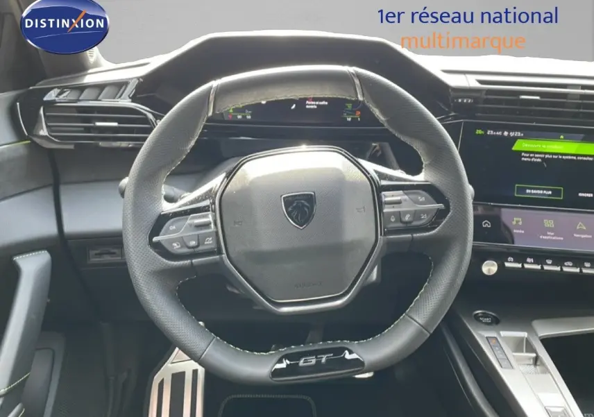 Vue intérieure centrée sur le volant GT de la Peugeot 308 gris Artense, avec tableau de bord digital et écran tactile visible.