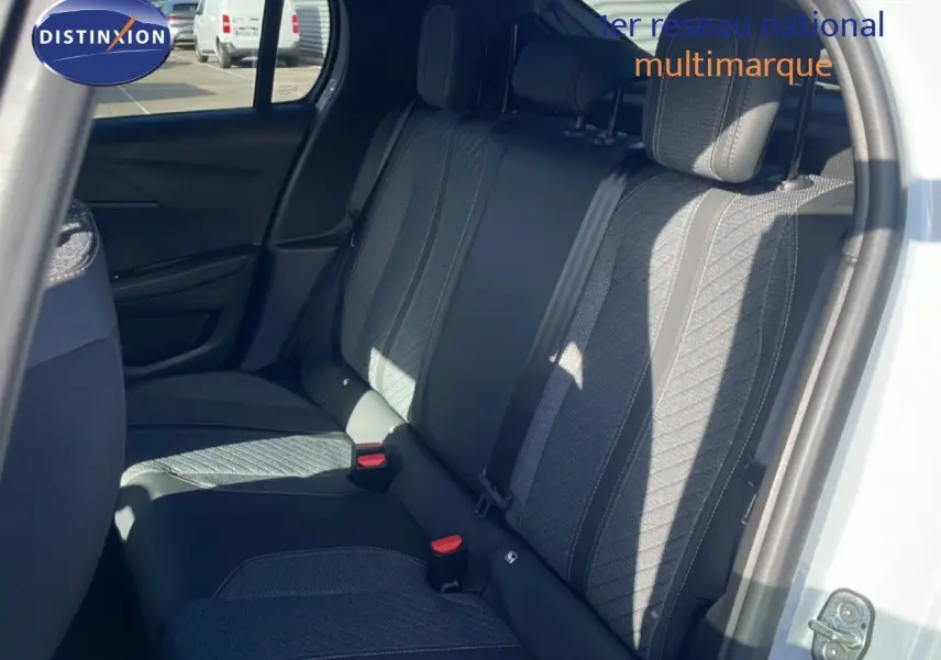 Vue intérieure côté arrière droit montrant les sièges arrière en tissu gris de la Peugeot 208 Hybrid blanche 2026.