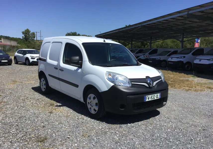 Renault Kangoo blanc vu en 3/4 avant droit, avec pare-chocs noirs et vitrage teinté, stationné sur un sol gravillonné.