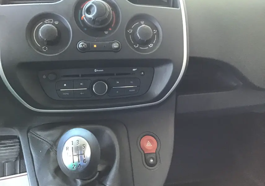 Gros plan sur la console centrale intérieure du Renault Kangoo blanc 2021, avec levier de vitesses manuel et commandes climatisation.