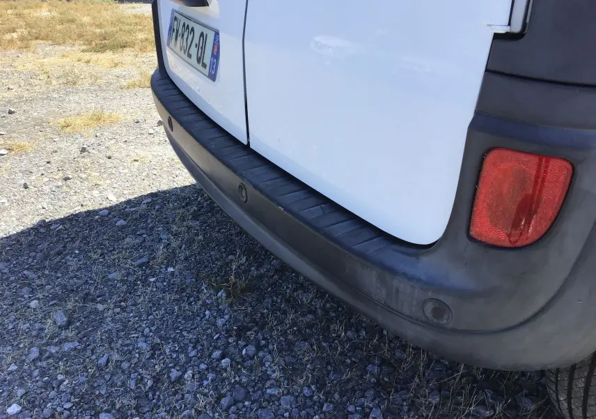 Gros plan sur le pare-chocs arrière noir et la porte blanche du Renault Kangoo 1.5 Blue dCi, avec feu arrière droit visible.