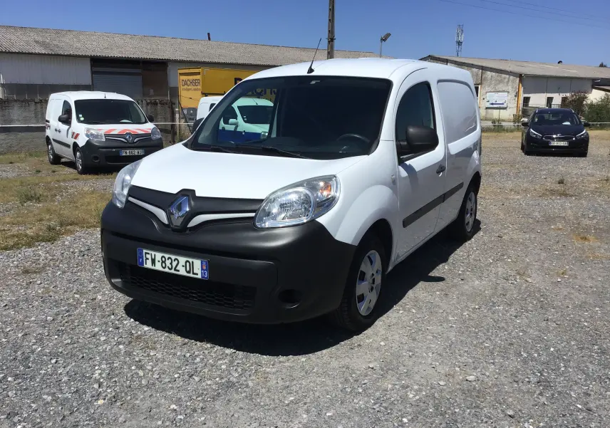 Renault Kangoo blanc vue 3/4 avant droit sur parking, avec pare-chocs noir et calandre marquée du logo Renault.