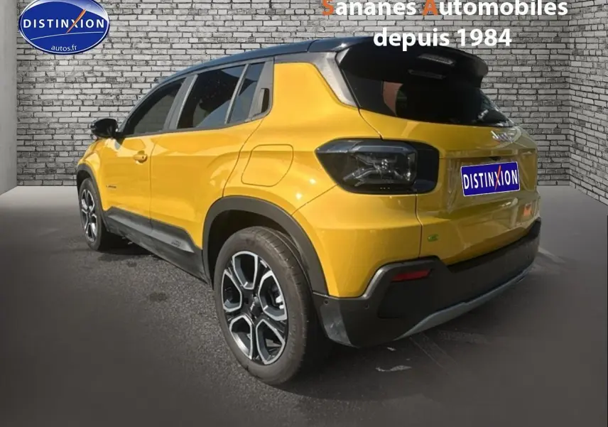 Vue 3/4 arrière droite d'un Jeep Avenger jaune foncé avec toit noir et jantes alliage distinctives.