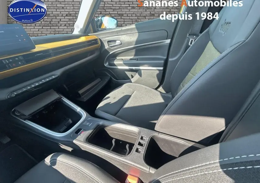 Intérieur avant droit du Jeep Avenger jaune foncé 2025 avec tableau de bord et sièges noirs, détails contrastants jaunes.