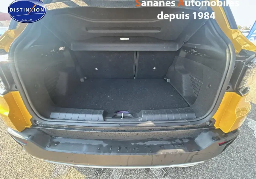 Coffre ouvert vu de l'arrière d'un Jeep Avenger jaune foncé, montrant l'espace de chargement vide.