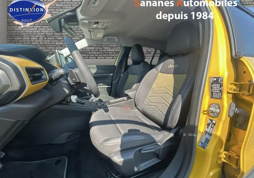 Vue intérieure côté conducteur du Jeep Avenger jaune foncé, mettant en valeur les sièges avec logo Jeep brodé.