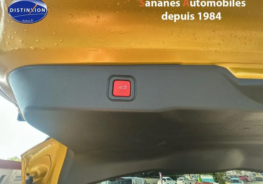 Bouton rouge d'ouverture électrique du hayon sur le coffre arrière jaune foncé d'un Jeep Avenger 2025.