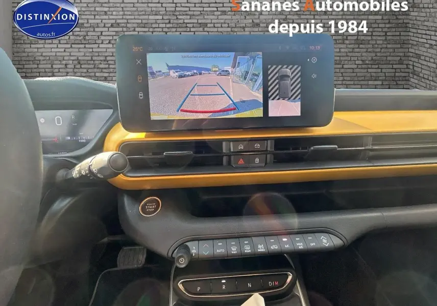Vue intérieure du tableau de bord du Jeep Avenger jaune foncé, avec écran tactile affichant la caméra de recul.