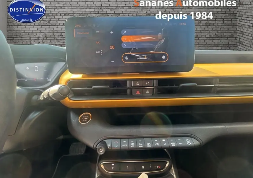 Vue intérieure du tableau de bord jaune foncé du Jeep Avenger 2025 avec écran tactile et commandes climatisation.