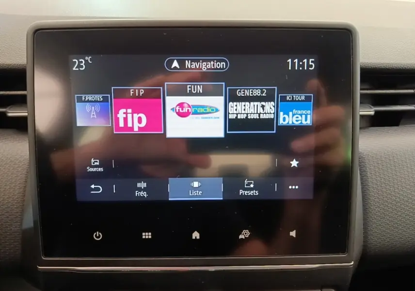 Écran tactile central de la Renault Clio Business E-TECH 140 blanc, affichant les stations radio et la navigation.