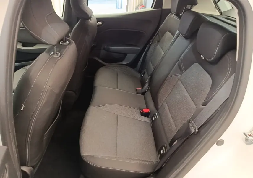 Vue latérale intérieure montrant la banquette arrière grise et noire d'une Renault Clio blanche, porte arrière ouverte.