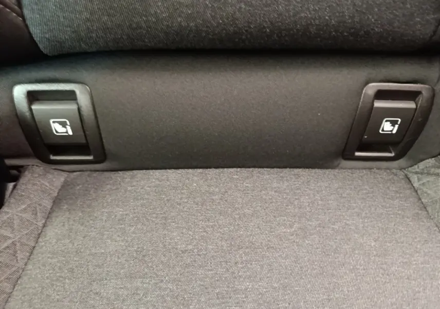 Détail des commandes de rabattement des sièges arrière en tissu gris dans une Renault Clio Business E-TECH 140 blanche.