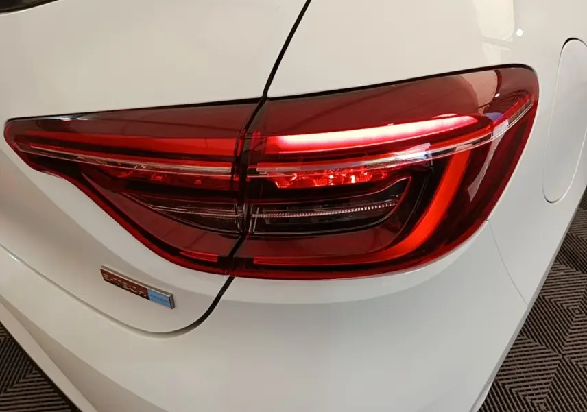 Gros plan sur le feu arrière droit rouge d’une Renault Clio Business E-TECH blanche, avec badge hybride visible.