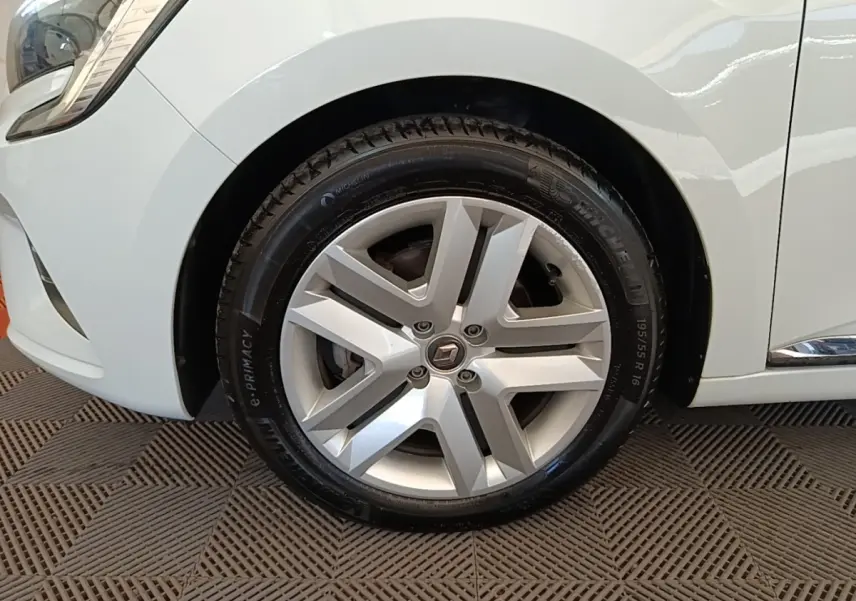 Gros plan sur la roue avant gauche d'une Renault Clio blanche, mettant en valeur la jante alliage et le pneu Michelin.