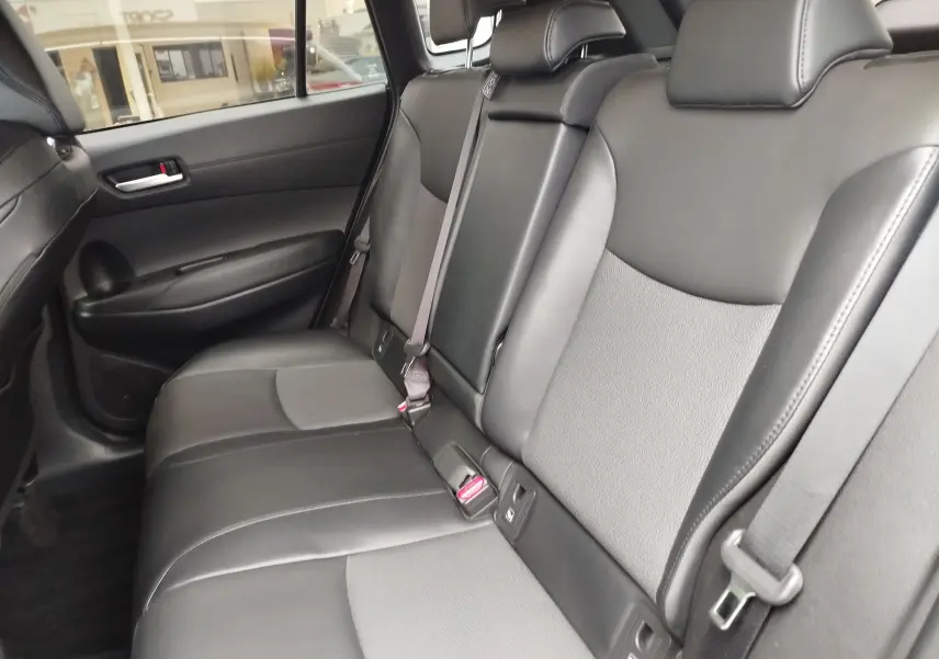 Vue intérieure côté droit des sièges arrière en cuir noir et tissu gris du Toyota Corolla Cross Hybrid 140 Luxury Limited 2025.