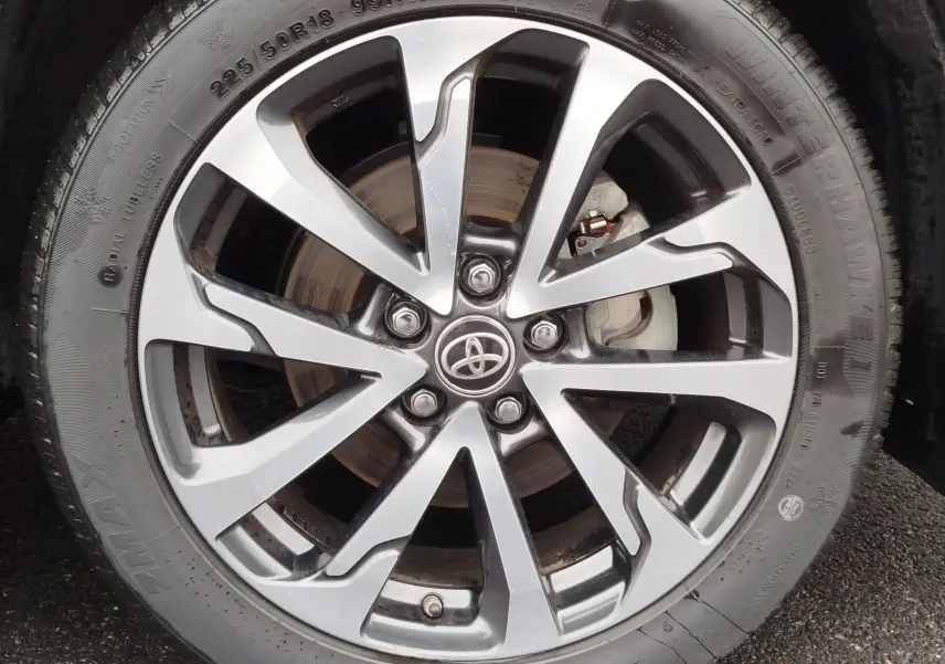 Gros plan sur la jante alliage bi-ton argent et noir avec logo Toyota, montée sur pneu hiver 225/50R18 du Corolla Cross 2025.
