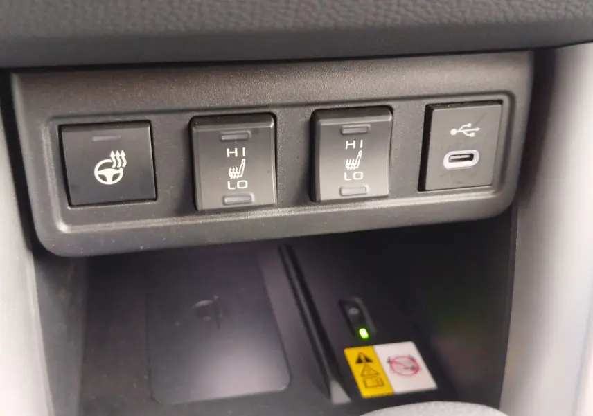 Gros plan sur les commandes de chauffage du volant et des sièges avec prise USB dans le Toyota Corolla Cross noir 2025.