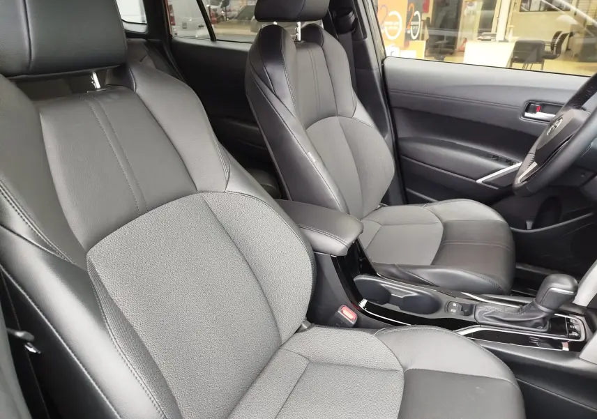 Vue intérieure rapprochée des sièges avant en cuir noir et tissu gris du Toyota Corolla Cross Hybrid 140 Luxury Limited 2025.