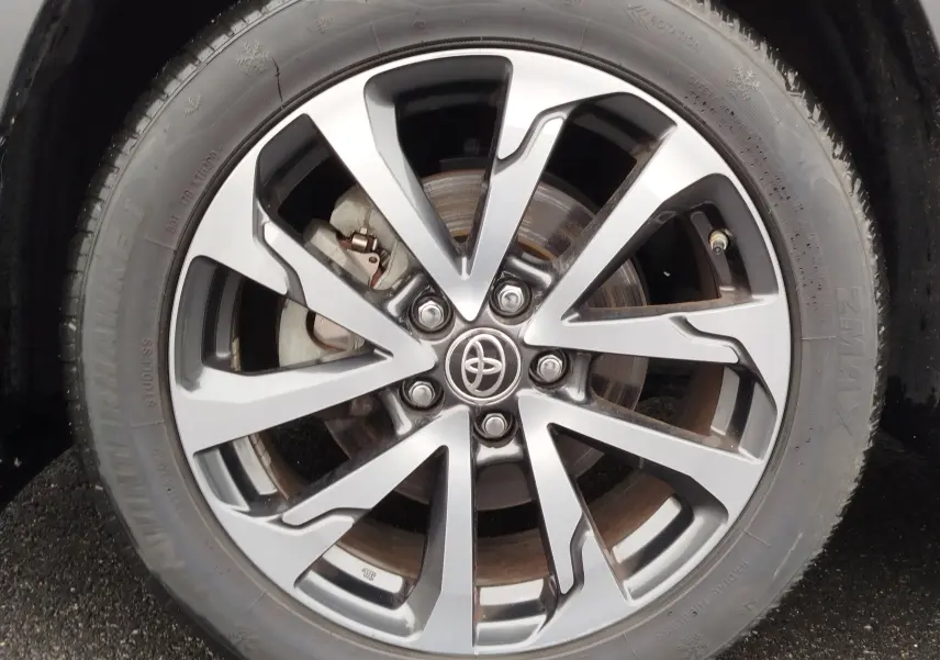 Gros plan sur la jante alliage bicolore et le pneu d'une Toyota Corolla Cross Hybrid 140 Luxury Limited noire.