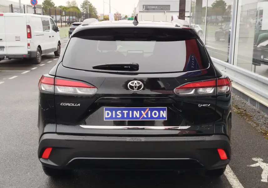 Vue arrière d'une Toyota Corolla Cross Hybrid 140 Luxury Limited noire, avec feux arrière allongés et logo distinctif.