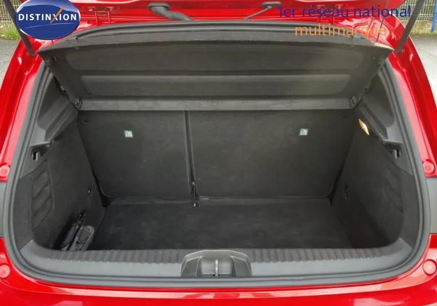 Coffre ouvert vu de l'arrière d'une Renault Clio 2025 rouge désir métal, montrant l'espace de chargement vide.