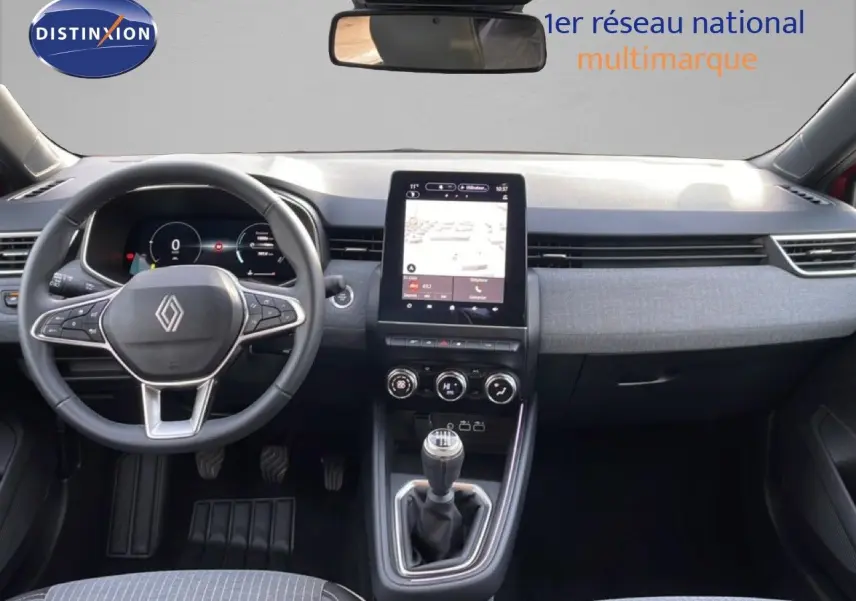 Vue intérieure frontale du tableau de bord de la Renault Clio rouge Désir Métal 2025 avec écran tactile et boîte manuelle.