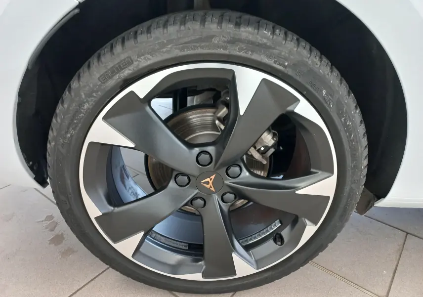 Gros plan sur la roue avant gauche de la CUPRA Leon blanc Nevada, avec jante alliage bicolore et logo CUPRA central.