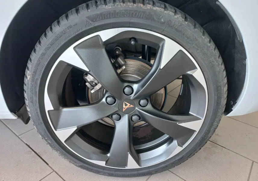 Gros plan sur la jante alliage bicolore gris et argent avec logo CUPRA d'une Leon Phase 2 Blanc Nevada 2025.