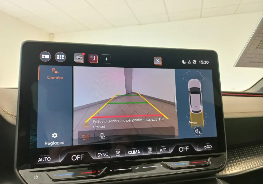 Écran tactile intérieur montrant la caméra de recul et l'aide au stationnement du CUPRA Leon blanc Nevada 2025.