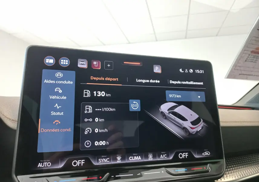 Écran tactile intérieur affichant les données de conduite d'une CUPRA Leon blanc Nevada vue en 3/4 arrière sur l'interface.