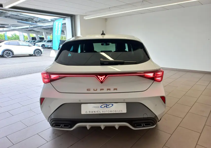 Vue arrière d'une CUPRA Leon blanche Nevada 2025 avec feux LED reliés et double sortie d'échappement intégrée.