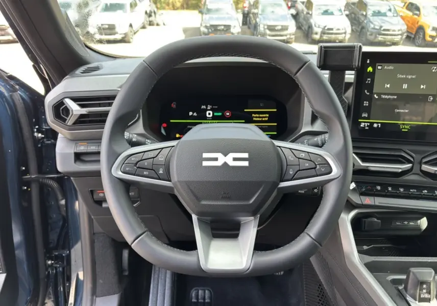 Vue intérieure centrée sur le volant cuir et le tableau de bord digital du Dacia Bigster Hybrid 155 en bleu indigo.