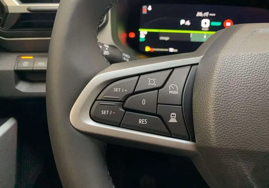 Gros plan sur les commandes au volant côté gauche du Dacia Bigster Hybrid 155 Journey Plus, volant cuir noir.