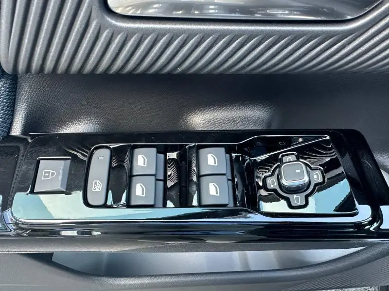 Gros plan sur les commandes de lève-vitres et réglage des rétroviseurs noirs sur la porte côté gauche d’un Citroën C5 Aircross.