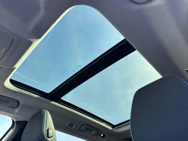 Toit panoramique en verre du Citroën C5 Aircross 2026 vu de l'intérieur avec ciel bleu visible.