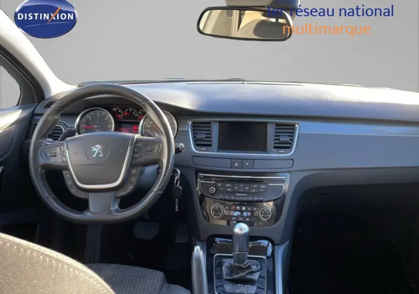 Vue intérieure avant du tableau de bord et du volant noir de la Peugeot 508 blanche, avec console centrale et écran tactile éteint.