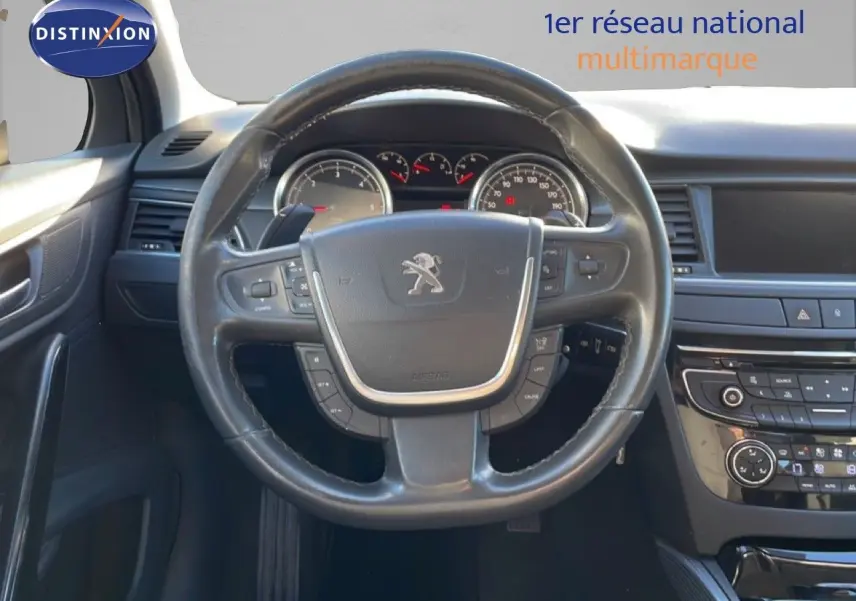 Vue intérieure centrée sur le volant noir de la Peugeot 508 blanche de 2012 avec tableau de bord et commandes visibles