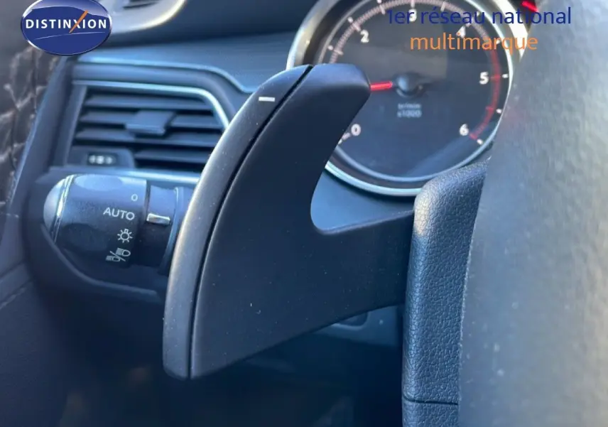 Gros plan sur la commande de palette de boîte automatique noire à gauche du volant dans l'habitacle d'une Peugeot 508 blanche de 2012.