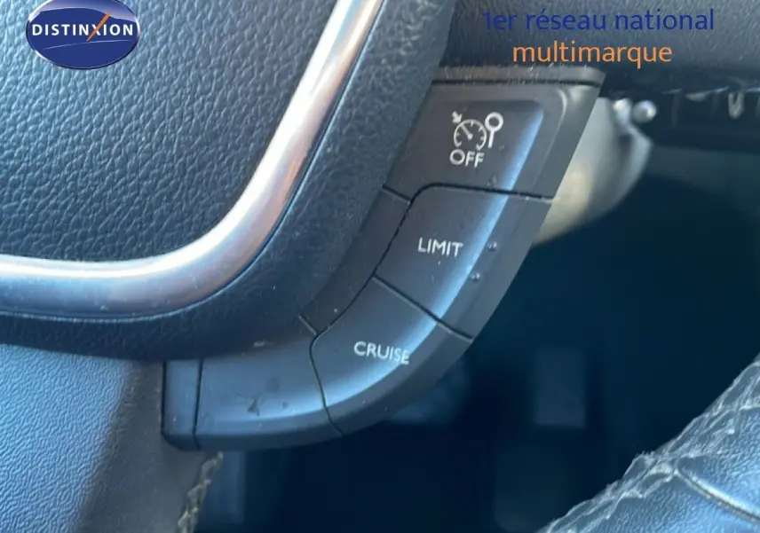 Gros plan sur les commandes de régulateur de vitesse au volant noir de la Peugeot 508 blanche de 2012.