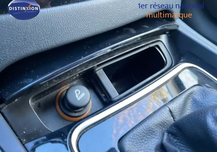 Gros plan sur la console centrale noire du Peugeot 508 blanc, mettant en valeur l'allume-cigare et le levier de vitesses cuir.