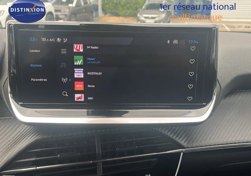 Écran tactile central du tableau de bord du Peugeot 2008 blanc Okenite, affichant les stations radio en extérieur.