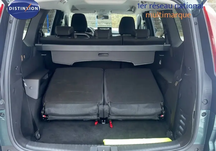 Coffre ouvert vu de l'arrière d'un Dacia Jogger vert cèdre métal avec sièges arrière rabattus et banquette noire.
