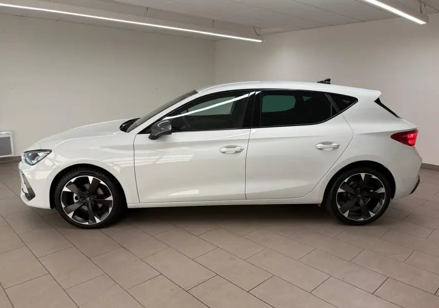 Vue de profil côté gauche d'une CUPRA Leon blanche Nevada 2025 avec jantes noires et vitres teintées.