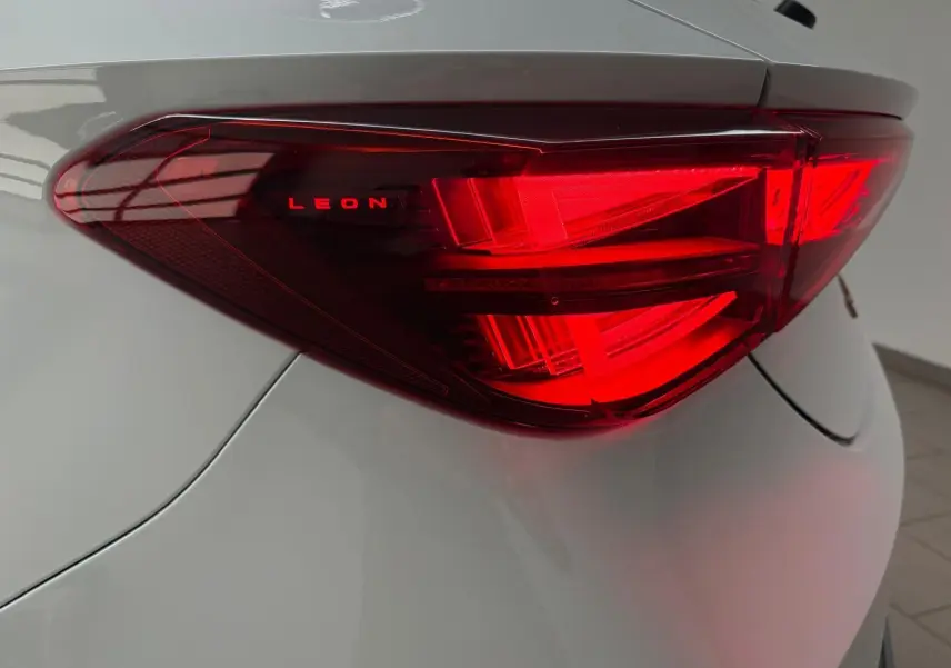 Gros plan sur le feu arrière droit rouge de la CUPRA Leon blanc Nevada avec inscription LEON lumineuse.