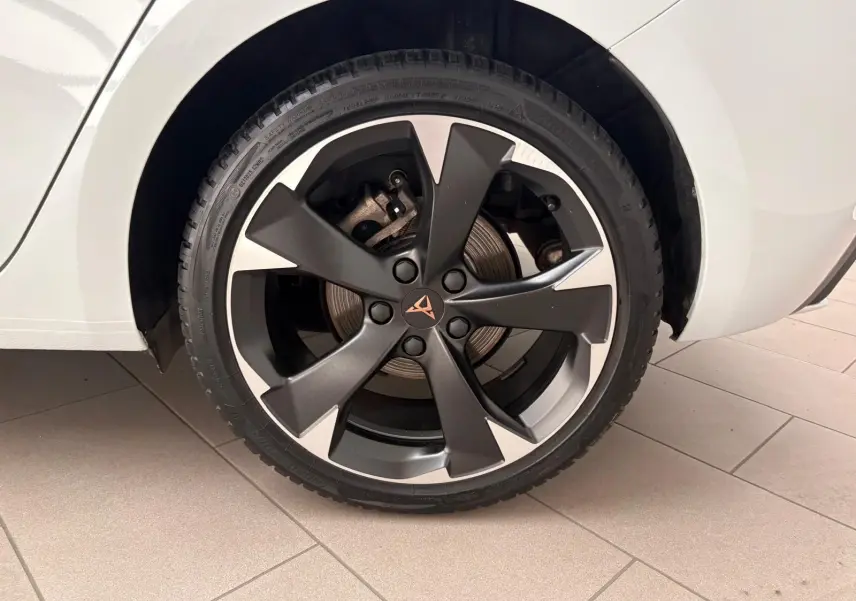 Gros plan sur la roue arrière droite d'une CUPRA Leon blanc Nevada avec jante alliage bicolore et logo CUPRA central.