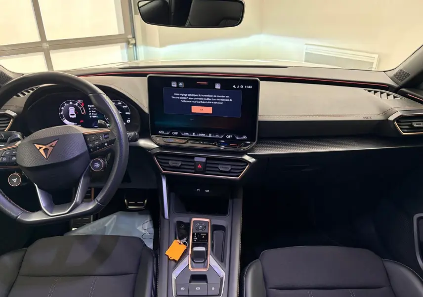 Vue intérieure du poste de conduite de la CUPRA Leon 2025, tableau de bord moderne avec écran tactile central et volant multifonction.
