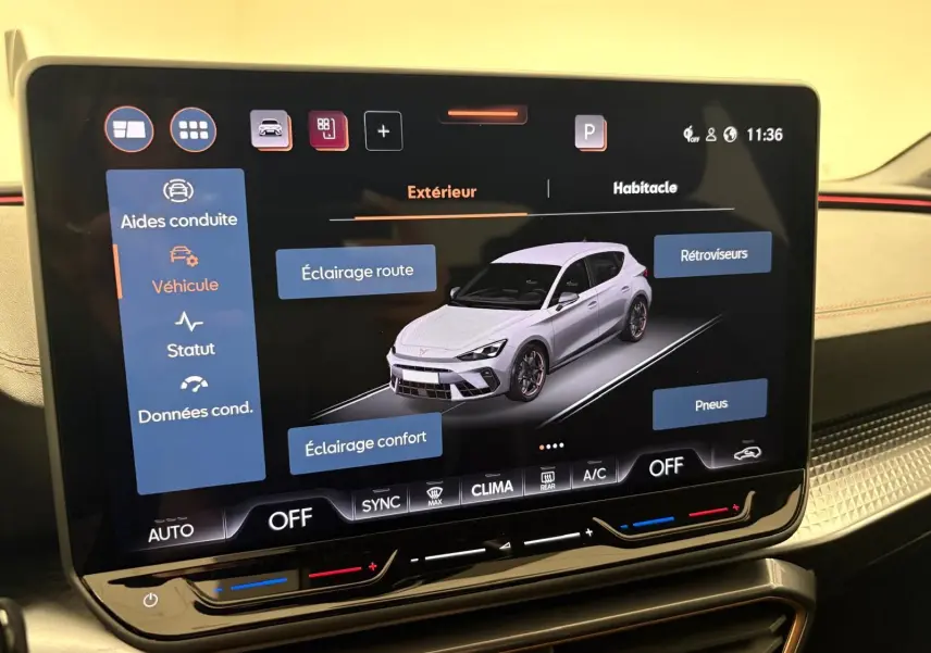 Écran tactile intérieur montrant une vue 3/4 avant d'une CUPRA Leon blanc Nevada avec options d'éclairage et pneus.