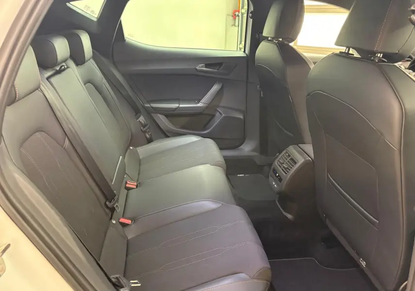 Vue intérieure arrière de la CUPRA Leon Phase 2 avec sièges noirs et détails de coutures contrastées visibles.